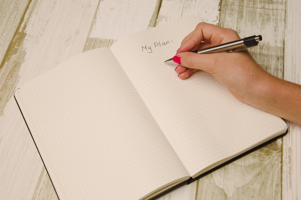 Woman writing "my plan" in notebook