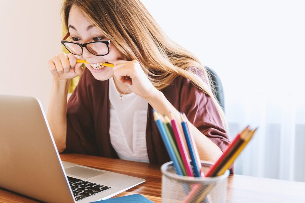 Girl stressed at her laptop biting a pencil